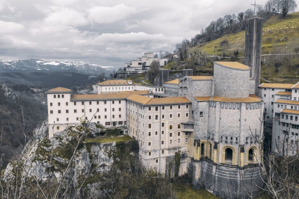 Santuario de Arantzazu sobre la roca, con las montañas al fondo