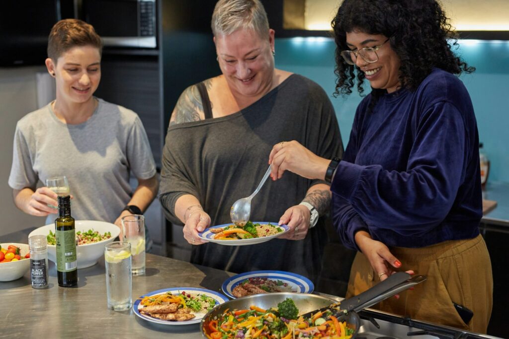 Tres personas sirviendo platos en la cocina